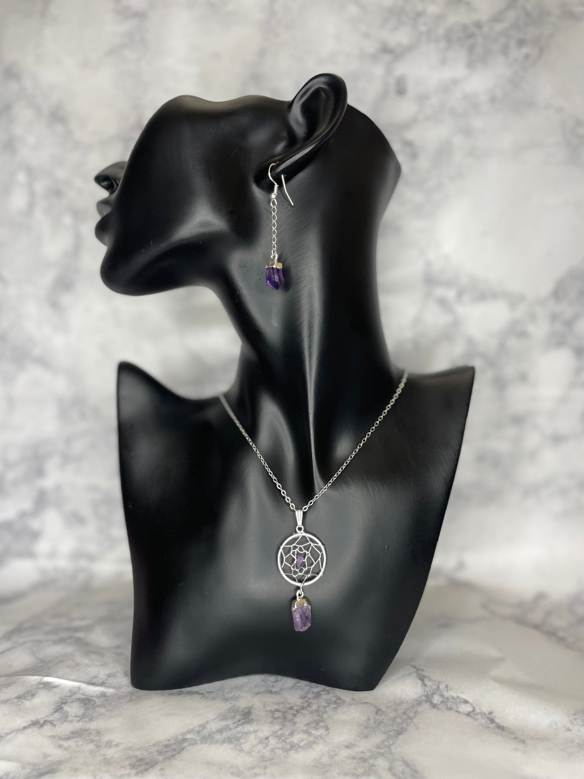 A photo of an amethyst dream catcher crystal necklace around a mannequin's neck with earrings