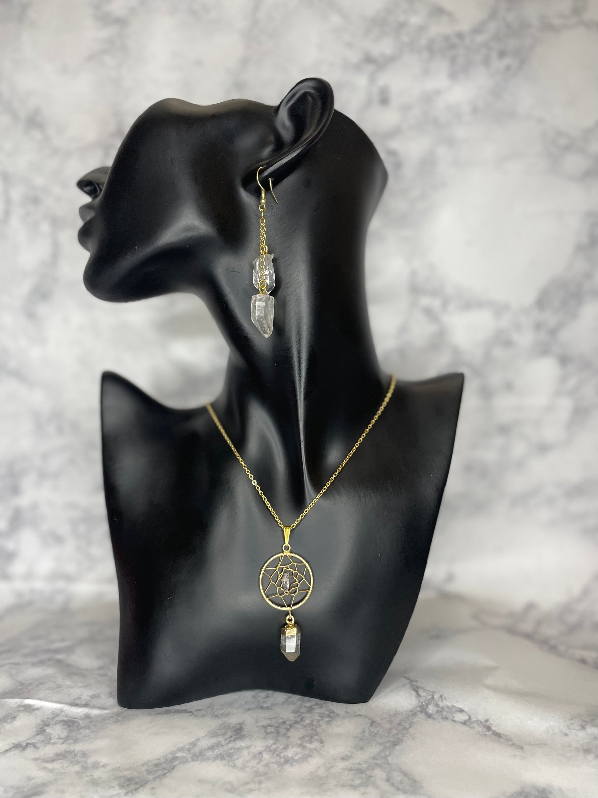 A photo of a clear quartz dream catcher crystal necklace around a mannequin's neck with earrings