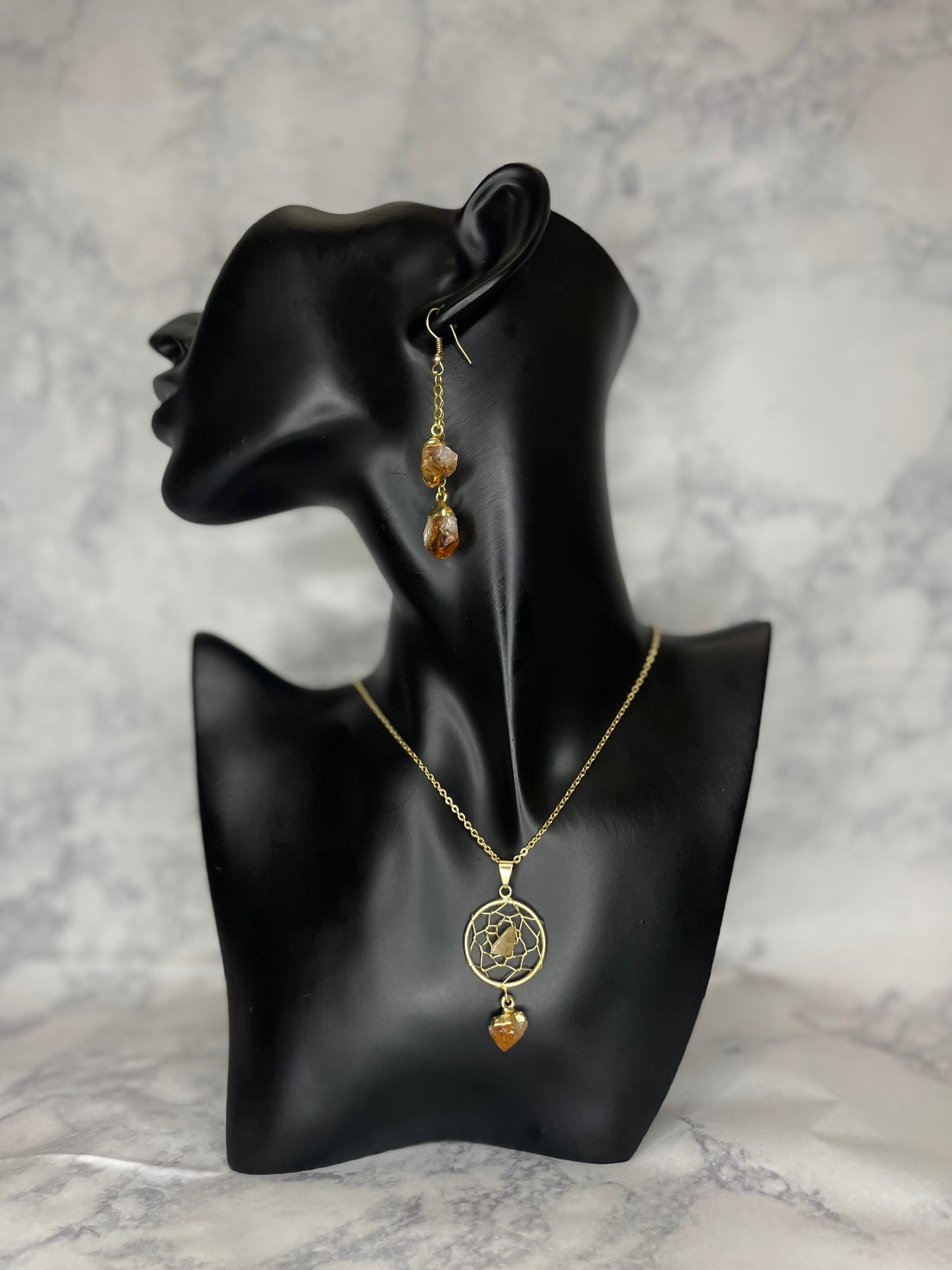 A photo of a citrine dream catcher crystal necklace around a mannequin's neck with earrings