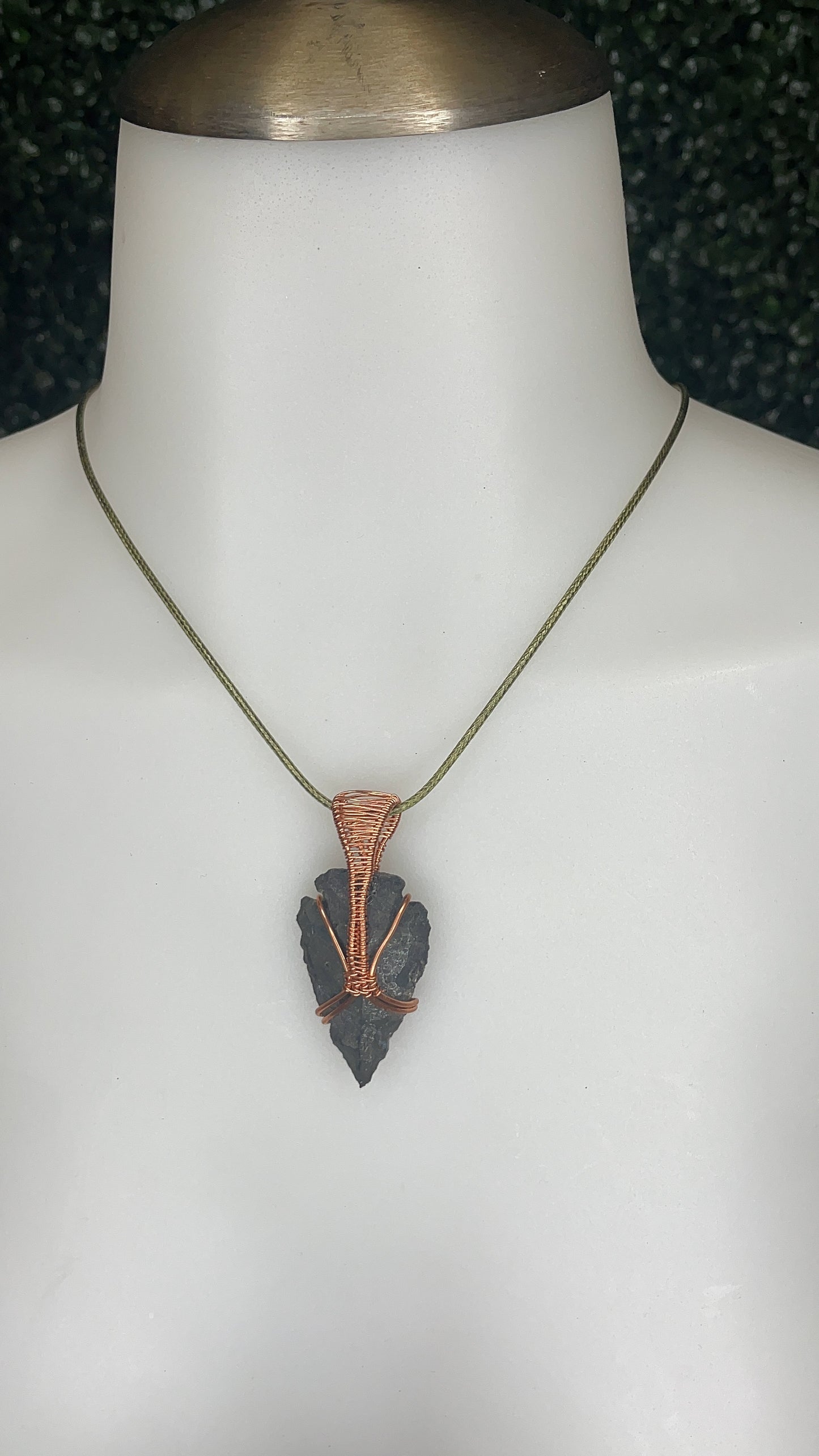 A photo of an arrowhead pendant on a mannequin's neck