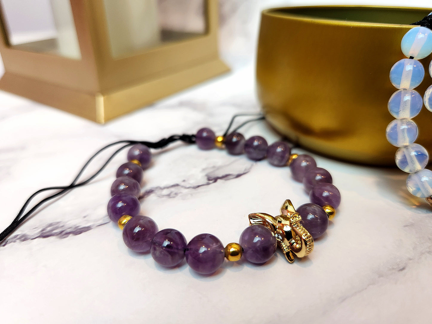 A close up photo of a purple elephant bracelet with a blue bracelet off to the side